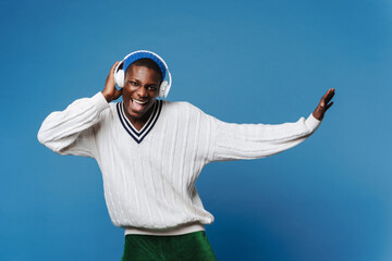 Black young man dancing and listening music with headphones