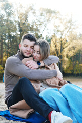 Young man and woman embrace with closed eyes. Date on the beach in cold weather