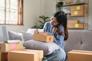 Small business entrepreneur SME freelance woman using phone call receive from customer checking product on stock at home office, online marketing packaging delivery box, SME e-commerce concept
