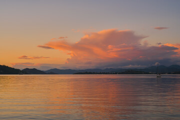 Evening warm landscape of Fethiye Bay, blurred background of a mountain range and cumulus clouds in the rays of the sun, an idea for a background