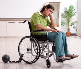 Young male invalid in wheel-chair suffering at home