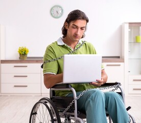 Young male invalid in wheel-chair suffering at home