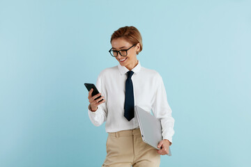 Smiling Businesswoman Messaging Smartphone. Caucasian Woman Using Mobile, Smiling, Holding Laptop. Modern Person Having Fun and Speaking on Call. Communication Concept