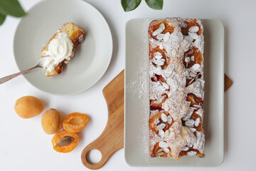rectangular appetizing homemade apricot pie on a rectangular plate, on a wooden cutting board. Next...