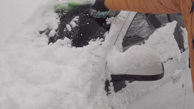 Driver clears his car from snow after heavy snowfall. Preparing for winter driving