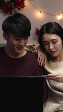 Vertical Screen: Happy smiling couple using credit card to internet shop online. Young lovers buying bargain things with special price on boxing day sale on pc.