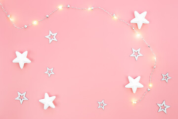 Pink Christmas background with garland and decorative stars, flat lay.