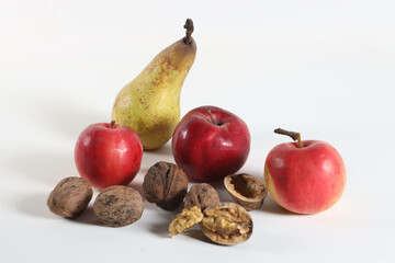 three bright red apples, pears and nuts on a white background