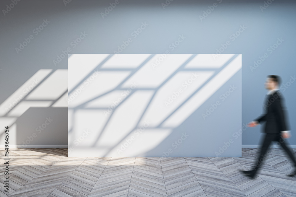 Poster side view of blurry businessman walking in spacious gallery interior with empty poster and sunlight 