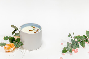 A large beautiful candle and eucalyptus twigs on a white background isolated.