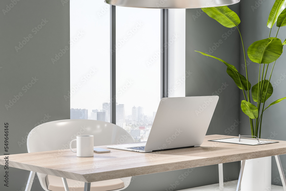 Poster perspective view on light wooden table with modern laptop and tea cup in sunlit room with city view 