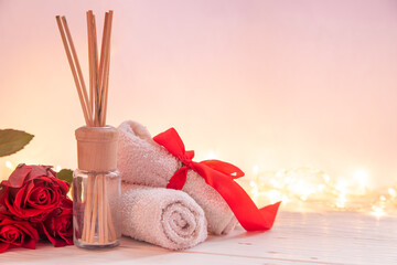 Spa composition for Valentine's Day with incense sticks, towel and red roses.
