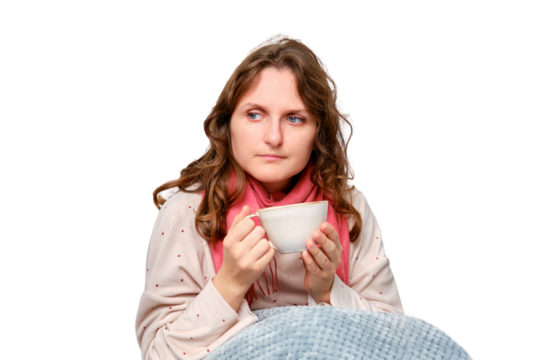 A sick woman is sitting on her home bed with a cup, isolated on a white background. Adult ill woman with a red scarf sitting on a bed in a white bedroom, female aged 35 years - Powered by Adobe
