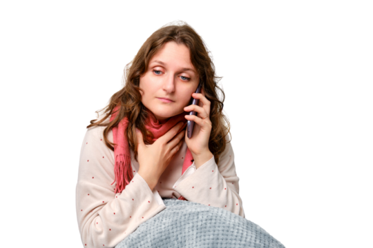 A sick woman is holding a sore throat with a phone in her hand, neck pain, isolated on a white background. Adult ill woman sitting on a home bed in a white bedroom, female aged 35 years