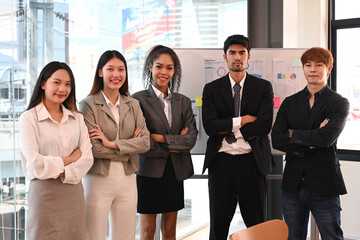 Obraz premium Diverse businesspeople standing with arms crossed near large window at modern office. Teamwork, cooperation and unity concept