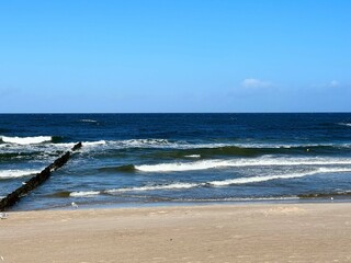A wooden breakwater on the Baltic Sea, protecting the shore from the waves, a wide sandy beach