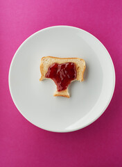 Toast with strawberry jam on white plate and bright pink
