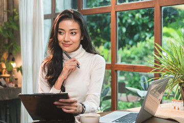 Entrepreneurs are using laptops to search websites and write new business ideas on the clipboard in the co-working space. She checks the inventory report in the store.