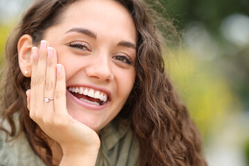 Happy woman smiling at camera showing engagement ring