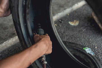 A man using an air die grinder with a sphere rotary burr to smoothen the surface of a damaged inner liner. Procedure in vulcanizing a punctured rubber tire.