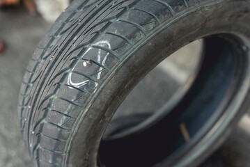 A damaged tire with a lodged screw marked with a white pen. Fixing and vulcanizing a flat tire.