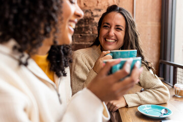 Happy friends enjoying coffee sitting in cafe