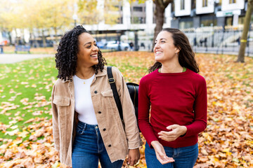 Smiling multiracial friends walking together in autumn park