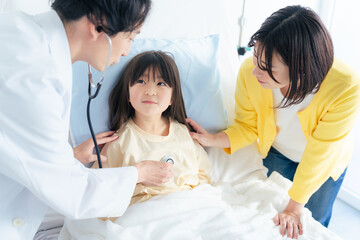 入院している女の子を診察する医師　小児科医