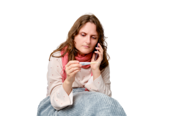 Sick woman calls the doctor on the phone with a thermometer in her hand, isolated on a white background. Adult ill woman wrapped in a red scarf sits on a home bed in a white bedroom, female age 35