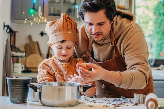 Smiling son cooking with father holding egg at table in kitchen
