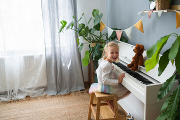Happy girl sitting on stool by piano at home