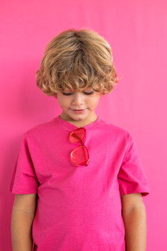 Boy looking down against pink background