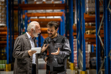 Warehouse manager and worker smiling and talking about work