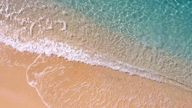 Sandy shore washing by clear turquoise waves. Aerial view from above. Summer paradise.