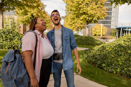 Cheerful young woman with man standing at park