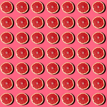 Pattern of halved grapefruits flat laid against pink background