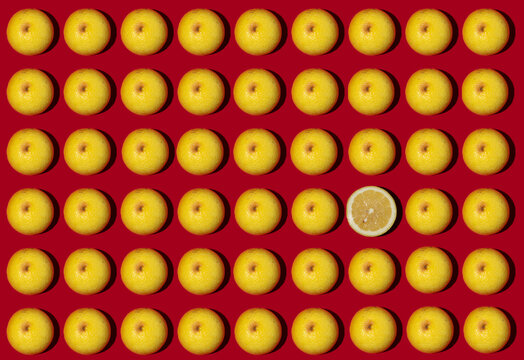 Pattern of halved lemons flat laid against red background with single one lying upside down
