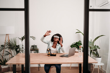 Freelancer wearing virtual reality headset with robotic model on desk at home