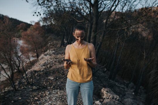 Woman looking at hand full of ash in forest