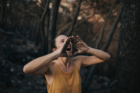 Woman shouting with dirty hands in burnt forest
