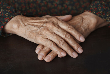 Senior woman with wrinkled hands on table