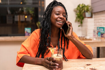 young african american woman laughing while talking by mobile phone