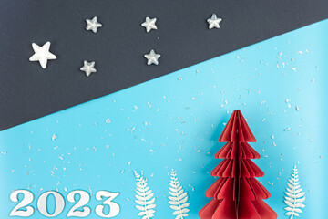 Christmas background with origami paper tree and number 2023, flat lay.