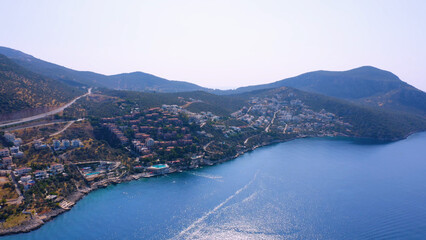 Fototapeta na wymiar Top view of beautiful resort city by sea on the background of mountains. Panorama of coastal town.
