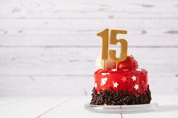 The number Fifteen on a red birthday cake on a light background