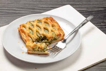 Pastel de hojaldre con crema de espinacas con tenedor. Puff pastry cake with spinach cream with a fork.