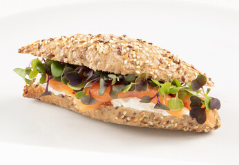 Baguette de cereales con queso crema, salmón y verdura sobre fondo blanco. Cereal baguette with cream cheese, salmon and vegetables on a white background.