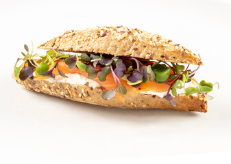 Baguette de cereales con queso crema, salmón y verdura sobre fondo blanco. Cereal baguette with cream cheese, salmon and vegetables on a white background.