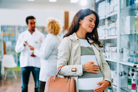 Jojful pregnant woman in pharmacy.