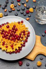 Cranberries and waffles on a gray plate.
